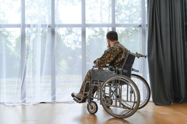 Un beau soldat assis dans un fauteuil roulant sur un fond gris.