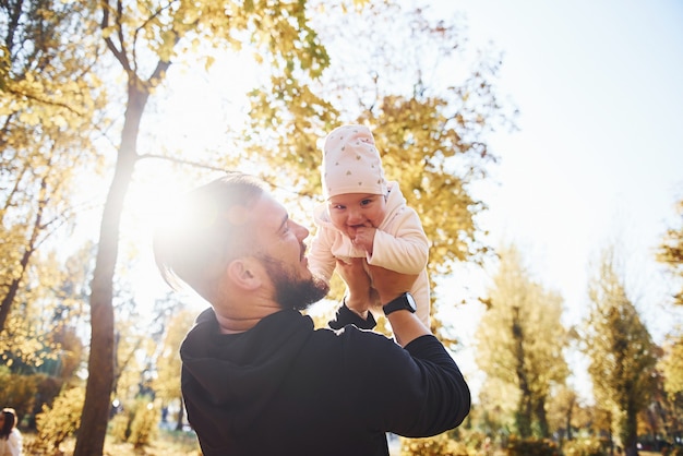 Photo beau soleil. père en vêtements décontractés avec son enfant est dans le magnifique parc d'automne.