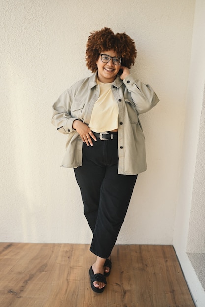 Beau sourire heureux sinueuse taille plus femme noire africaine cheveux afro posant un jean tshirt beige