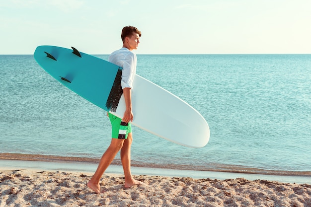 Beau surfeur tenant sa planche de surf