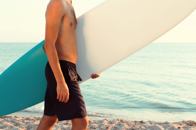 Beau surfeur tenant sa planche de surf