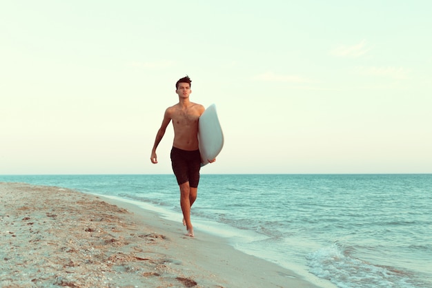 Beau surfeur tenant sa planche de surf