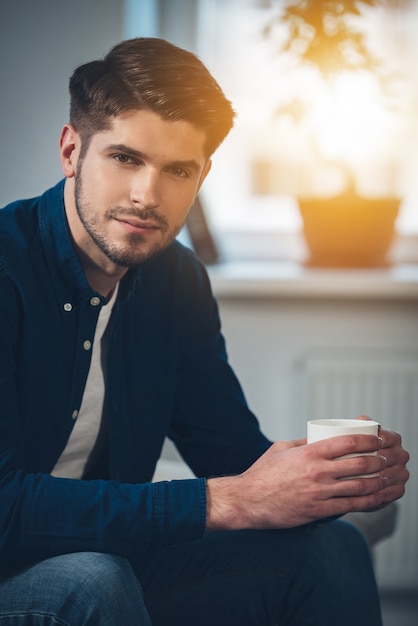 beau avec une tasse de café. beau jeune homme tenant une tasse de café et regardant la caméra