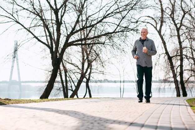 Beau temps. Homme senior optimiste en cours d'exécution et profiter de la nature