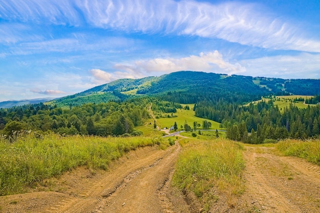 Beau terrain avec chemin de terre et forêt couverte de collines derrière la montagne et le ciel avec fond de paysage de granges