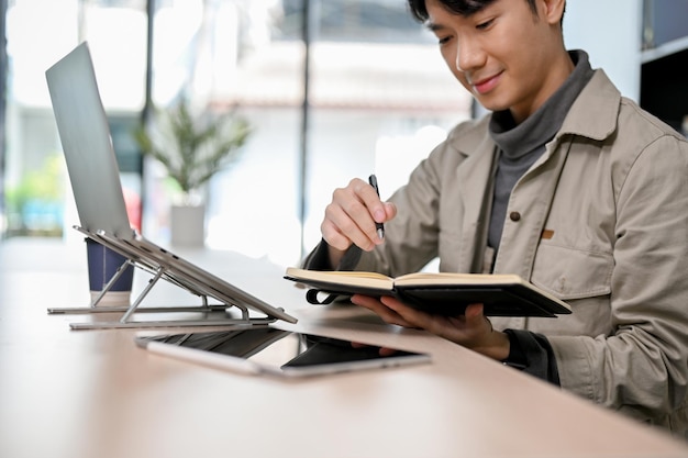 Beau travailleur de bureau masculin asiatique travaillant à distance dans l'espace de coworking du café