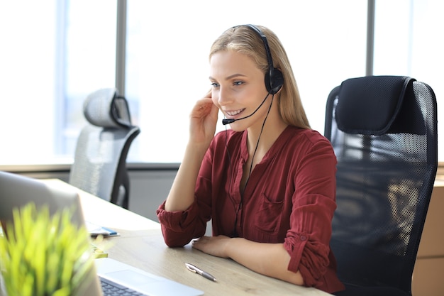 Un beau travailleur du centre d'appels dans les écouteurs travaille dans un bureau moderne.