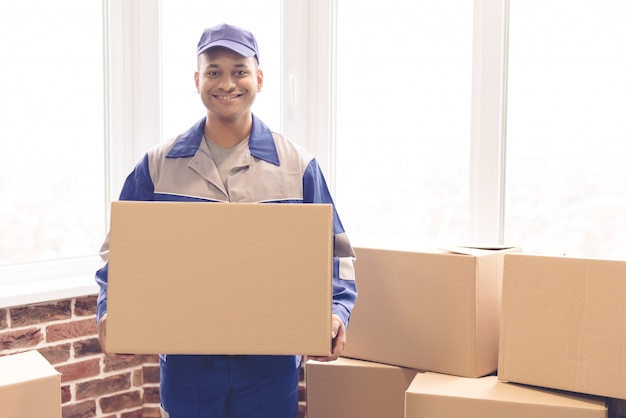 Beau travailleur en uniforme bleu est titulaire d'une boîte.