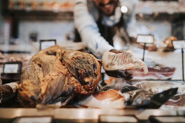 Beau vendeur masculin d'âge moyen travaillant au supermarché ou à l'épicerie et vendant des produits de charcuterie.