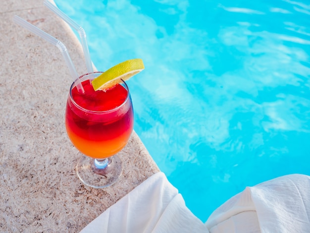 Beau verre avec un cocktail au bord de la piscine