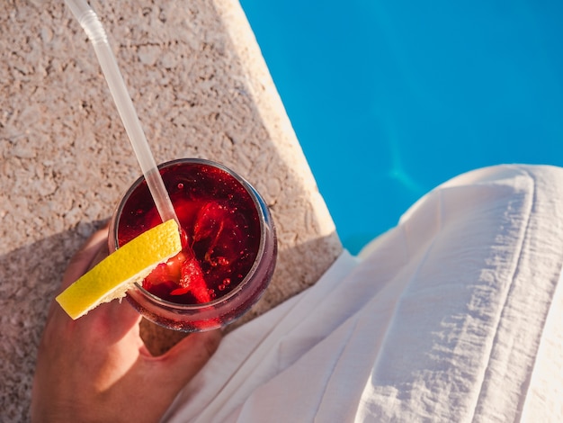 Beau verre avec un cocktail au bord de la piscine