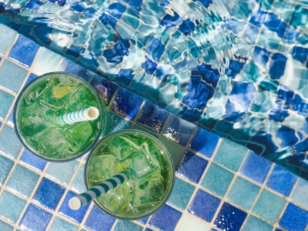 Beau verre avec un cocktail rafraîchissant sur le fond de la piscine