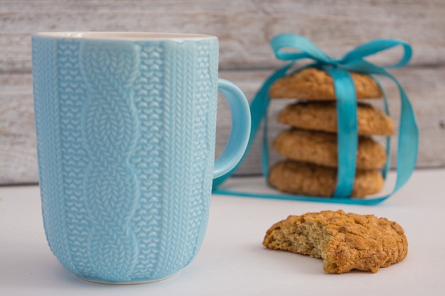 Beau verre à thé bleu et un morceau de biscuits à l&#39;avoine sur un vieux dessus de table en bois.