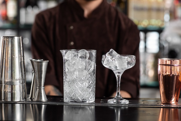 Beau verre transparent avec glace et support de tasse en acier sur le comptoir du bar en arrière-plan