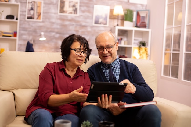 Beau vieux couple utilisant une tablette numérique pour discuter avec leur famille. Personnes âgées utilisant la technologie moderne