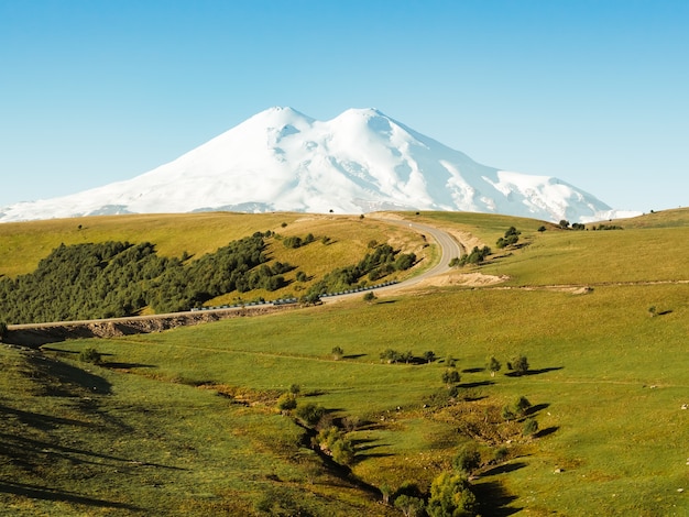 Un beau virage de la route à travers les vertes collines du Caucase jusqu'à Elbrouz.