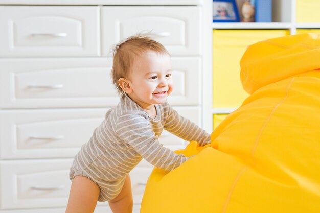 Beau visage de bébé garçon riant adorable. Un enfant souriant est assis sur une chaise