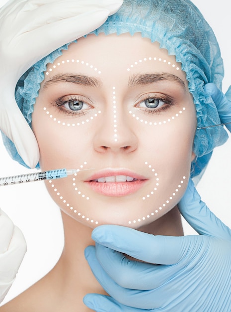 Le beau visage féminin avec des lignes pendant l'opération de chirurgie plastique de la cosmétologie
