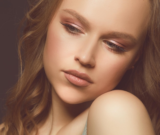 Beau visage de femme avec une peau propre bronzée isolé sur noir