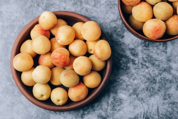 Beaucoup d'abricots jaunes mûrs se bouchent dans une vaisselle sur la table