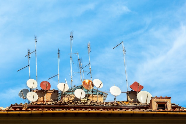 Beaucoup d'antennes paraboliques sur la maison sur fond de ciel bleu en Italie.