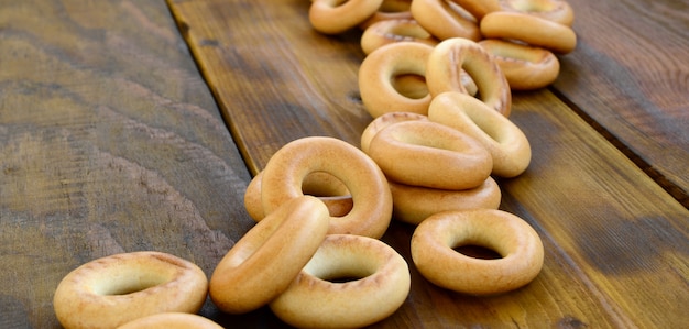 Beaucoup de bagels jaunes frais se trouvent à la surface du vieux bois sombre.