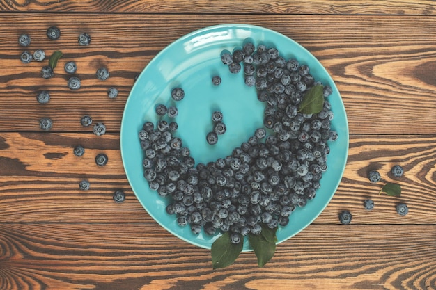 Beaucoup de belles myrtilles juteuses et étonnantes dans un plat bleu sur fond en bois foncé beau fond d'art alimentaire vue de dessus espace de copie