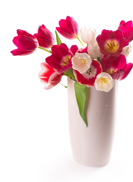 Beaucoup de belles tulipes colorées avec des feuilles dans un vase en verre isolé sur fond transparent. Photo avec des fleurs printanières fraîches pour tout design festif