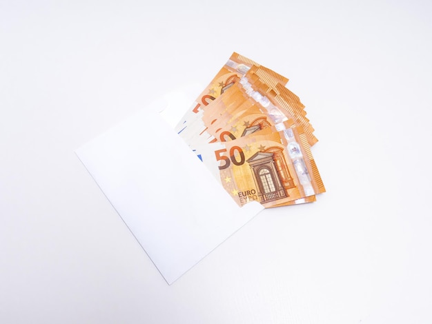 Beaucoup de billets de cinquante euros dans une enveloppe blanche sur fond blanc