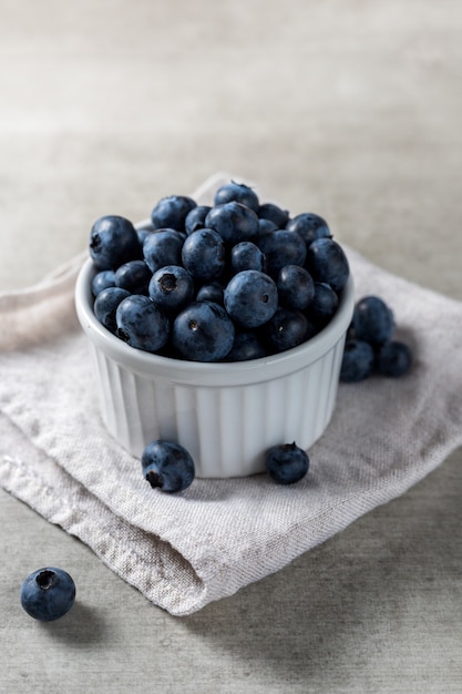 Beaucoup de bleuets frais délicieux sur un pot blanc sur une table en bois.