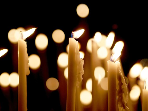 Photo beaucoup de bougies allumées avec une faible profondeur de champ bougies allumées sur une surface sombre