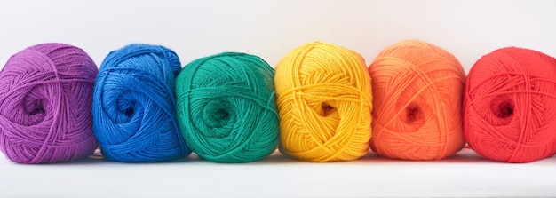 Beaucoup de boules de fils multicolores sur tissu tricoté sur fond de bois blanc Fil de fleurs colorées vives tricot et crochet Concept de couture ou de tricot