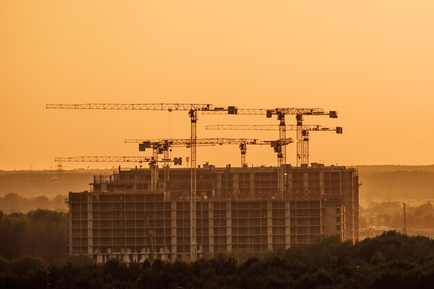 Beaucoup de chantier de construction de tours avec grues et bâtiment avec fond de ciel du soir