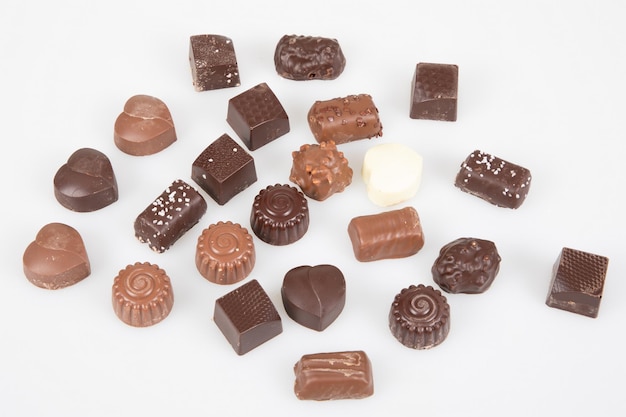 Beaucoup de chocolat noir et au lait de différentes formes barre de bonbons pralinés en vue de dessus sur fond blanc