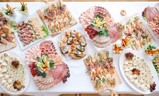 beaucoup de collations à base de viande sur une longue table blanche sur des assiettes de plateaux. photo de haute qualité