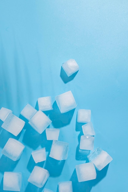 Beaucoup de cubes de glace à l'ombre de feuilles de palmier sur un fond bleu