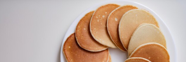 Beaucoup de délicieuses crêpes appétissantes allongées sur une plaque blanche en vue de dessus du cercle