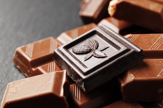 Beaucoup de différents morceaux de chocolat sur un fond en pierre sombre.