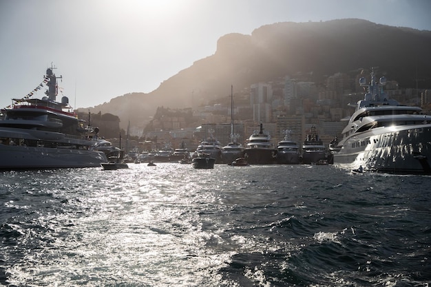 Beaucoup d'énormes yachts sont dans le port hercule de monaco au coucher du soleil la montagne est sur fond de fond magique ...