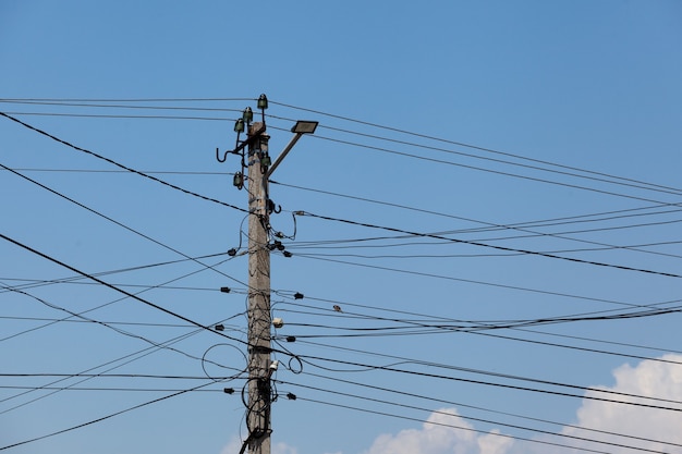 Beaucoup de fils électriques sur un pilier en béton Mise au point sélective des nuages de ciel bleu