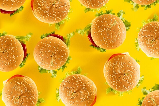 Beaucoup de hamburgers malsains et malsains savoureux avec du ketchup et des légumes sur un fond brillant et jaune. Vue de dessus avec espace de copie.