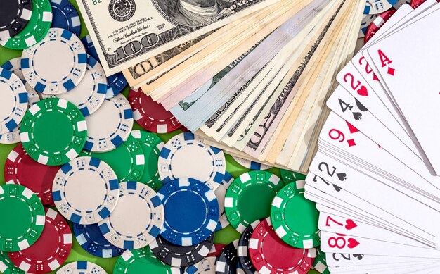 Beaucoup de jetons de poker avec des cartes et des dollars sur la table