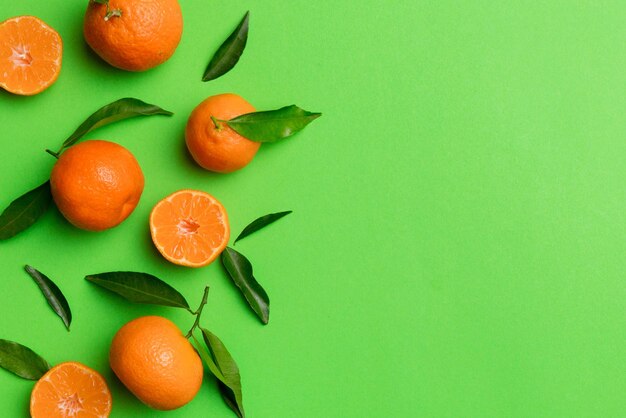 Photo beaucoup de mandarines fraîches et mûres avec des feuilles vertes sur fond coloré, vue de dessus, espace pour le texte