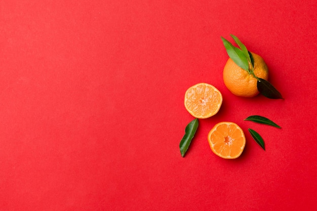 Beaucoup de mandarines mûres fraîches avec des feuilles vertes sur fond coloré vue de dessus espace pour le texte