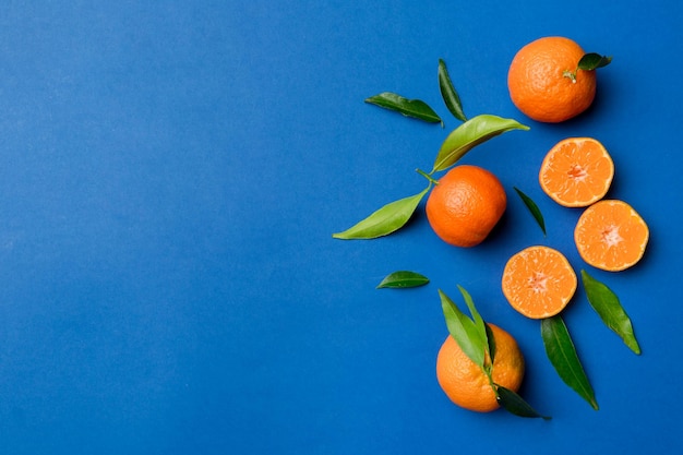 Beaucoup de mandarines mûres fraîches avec des feuilles vertes sur fond coloré vue de dessus espace pour le texte