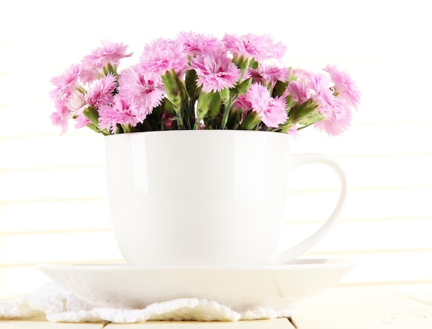 Beaucoup de petits clous de girofle roses dans une tasse sur fond de bois