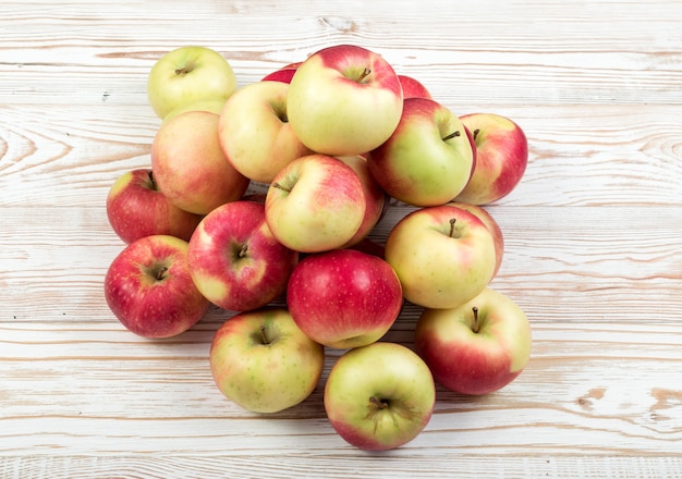 Beaucoup de pommes molles rouges et vertes prêtes pour la vue de dessus de production de jus. Trois kilogrammes de pomme biologique empilés dans une pile sur une surface rustique en bois