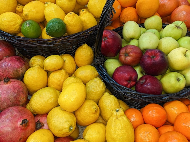 Beaucoup de pommes rouges et vertes dans un panier parmi les citrons et autres fruits