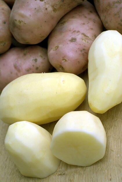 Photo beaucoup de pommes de terre pelées et non pelées sur le bureau de la cuisine dans le processus de cuisson des aliments vue rapprochée