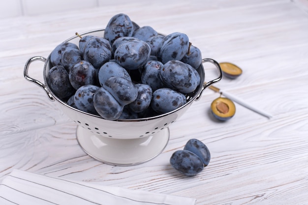 Beaucoup de prunes juteuses mûres dans un bol sur la table.